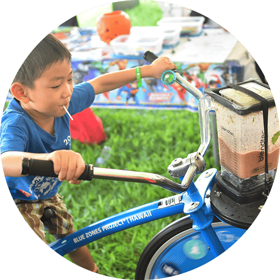 Young boy riding the Blue Zones Project blender bike making a smoothie