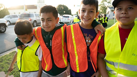 Four students in safety vests walking to school