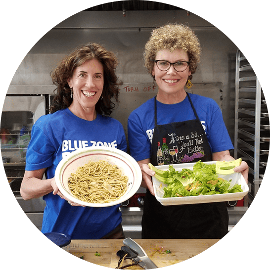 Two volunteers showing off plant-based dishes.